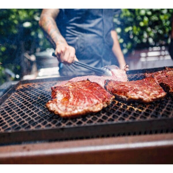 Man grilling meat on a large grill for catering events
