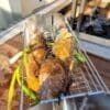 Grilling fish in a rotisserie basket on a wood grill.