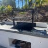 All black iron wood burning grill with adjustable grill grate.