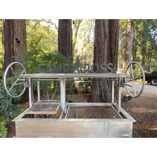 An all stainless Argentine Gaucho grill with two large hand cranks for cooking over live fire.
